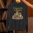 Women's Unearth a Story Summer 2026 Dinosaur Reading Books Dino Unisex Hoodie Women's Unearth a Story Summer 2026 Dinosaur Reading Books Dino Unisex Hoodie