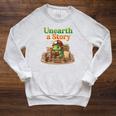 Unearth a Story Summer 2026 Dinosaur Reading Books Dino Raglan Sleeve Sweatshirt Heather Mustard