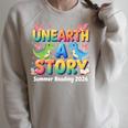Summer Reading Unearth A Story Dinosaur Books 2026 Raglan Sleeve Sweatshirt Heather Forest Summer Reading Unearth A Story Dinosaur Books 2026 Raglan Sleeve Sweatshirt Heather Forest