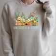 Unearth a Story Dinosaur 2026 Summer Reading Program Book Raglan Sleeve Sweatshirt Heather Forest Unearth a Story Dinosaur 2026 Summer Reading Program Book Raglan Sleeve Sweatshirt Heather Forest