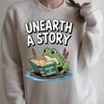 Unearth a Story Frog Reading a Book Summer 2026 Premium Tri-Blend Raglan Sleeve Sweatshirt Heather Forest Unearth a Story Frog Reading a Book Summer 2026 Premium Tri-Blend Raglan Sleeve Sweatshirt Heather Forest