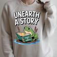 Unearth a Story Frog Reading a Book Summer 2026 Raglan Sleeve Sweatshirt Heather Forest Unearth a Story Frog Reading a Book Summer 2026 Raglan Sleeve Sweatshirt Heather Forest