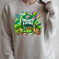 Unearth a Story Library Summer Reading 2026 Dinosaur Book Raglan Sleeve Sweatshirt Heather Forest