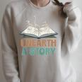 Unearth A Story Skeleton Dinosaur Book Summer Reading 2026 Raglan Sleeve Sweatshirt Heather Forest Unearth A Story Skeleton Dinosaur Book Summer Reading 2026 Raglan Sleeve Sweatshirt Heather Forest