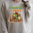 Unearth a Story Summer 2026 Dinosaur Reading Books Dino Raglan Sleeve Sweatshirt Heather Forest