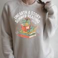 Unearth A Story Summer Reading 2026 Dinosaur Books Raglan Sleeve Sweatshirt Heather Forest Unearth A Story Summer Reading 2026 Dinosaur Books Raglan Sleeve Sweatshirt Heather Forest
