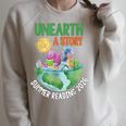 Unearth A Story Summer Reading Program 2026 Animals Book Raglan Sleeve Sweatshirt Heather Forest Unearth A Story Summer Reading Program 2026 Animals Book Raglan Sleeve Sweatshirt Heather Forest