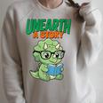 Women's Unearth a Story Summer Reading 2026 Triceratops Dino Book Raglan Sleeve Sweatshirt Heather Forest Women's Unearth a Story Summer Reading 2026 Triceratops Dino Book Raglan Sleeve Sweatshirt Heather Forest