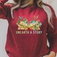 Unearth a Story Dinosaur 2026 Summer Reading Program Book Raglan Sleeve Sweatshirt Heather Dust Unearth a Story Dinosaur 2026 Summer Reading Program Book Raglan Sleeve Sweatshirt Heather Dust