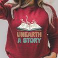 Unearth A Story Skeleton Dinosaur Book Summer Reading 2026 Raglan Sleeve Sweatshirt Heather Dust Unearth A Story Skeleton Dinosaur Book Summer Reading 2026 Raglan Sleeve Sweatshirt Heather Dust