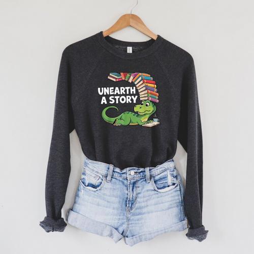 Summer Reading 2026 Unearth a Story Theme Dinosaur Book Nerd Raglan Sleeve Sweatshirt - Bookorys DE