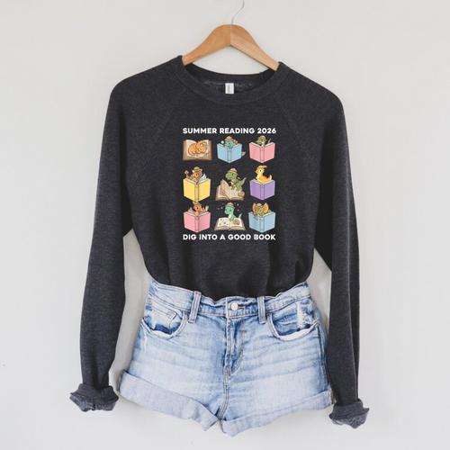 Summer Reading 2026 Unearth A Story Dinosaur Books Readers Raglan Sleeve Sweatshirt - Bookorys