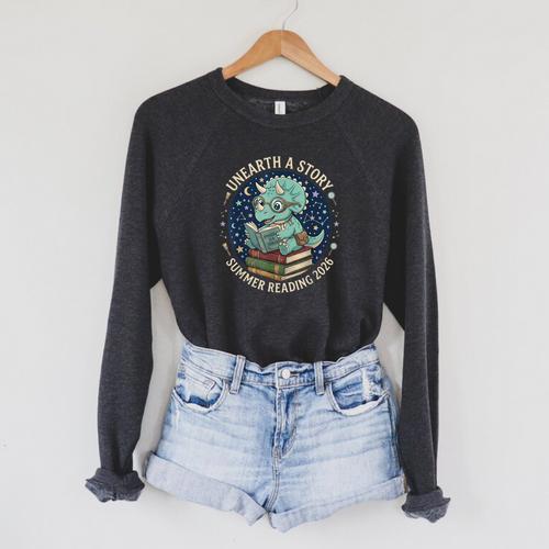 Unearth A Story Summer Reading 2026 Cute Dinosaur Reading Raglan Sleeve Sweatshirt - Bookorys