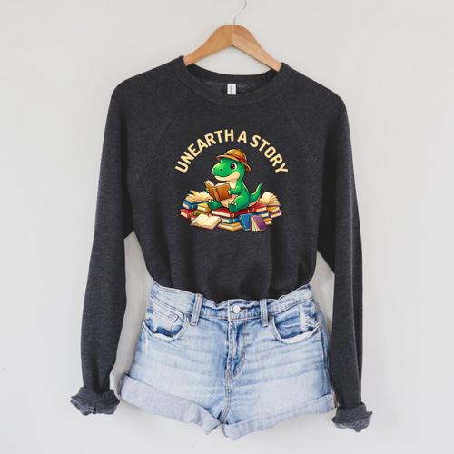 Unearth A Story Summer Reading 2026 Dinosaur Book Floral Raglan Sleeve Sweatshirt - Bookorys DE