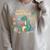 Lost In a Good Book Cute Reading Dinosaur Illustration Raglan Sleeve Sweatshirt Heather Forest