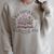 A New Chapter Retired 2026 Begins Retirement Wildflower Book Raglan Sleeve Sweatshirt Heather Forest