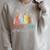 Unearth A Story Summer Reading 2026 Book Wildflowers Raglan Sleeve Sweatshirt Heather Forest