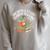 Unearth A Story Summer Reading 2026 Dinosaur Books Raglan Sleeve Sweatshirt Heather Forest Unearth A Story Summer Reading 2026 Dinosaur Books Raglan Sleeve Sweatshirt Heather Forest