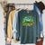 Unearth a Story Library Summer Reading 2026 Dinosaur Book Raglan Sleeve Sweatshirt Heather Blue Lagoon