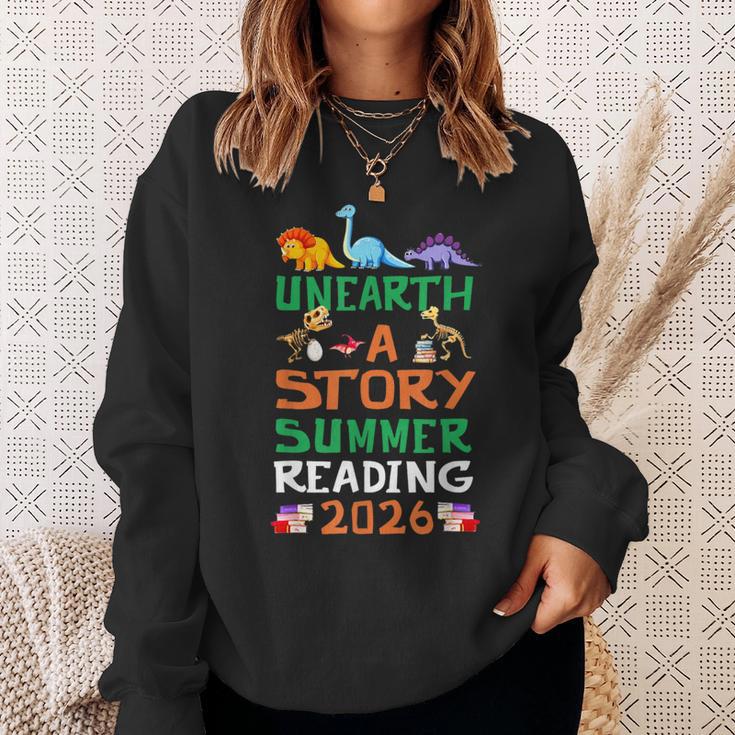 Unearth A Story Summer Reading Program 2026 Dinosaur Book Sweatshirt Gifts for Her Unearth A Story Summer Reading Program 2026 Dinosaur Book Sweatshirt Gifts for Her
