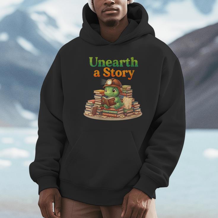 Women's Unearth a Story Summer 2026 Dinosaur Reading Books Dino Unisex Hoodie Women's Unearth a Story Summer 2026 Dinosaur Reading Books Dino Unisex Hoodie