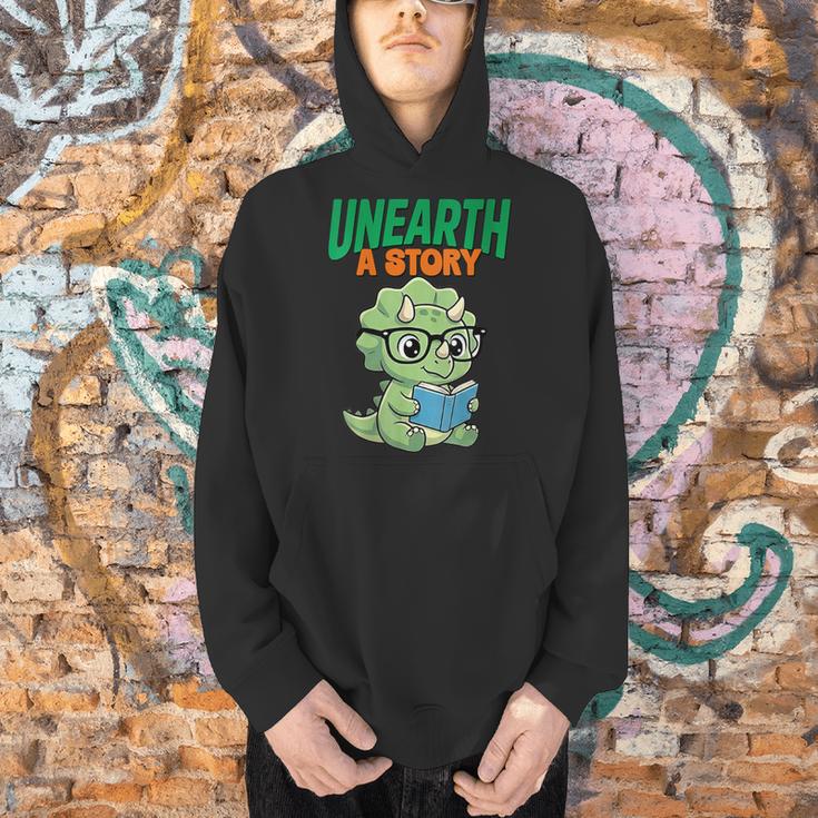 Women's Unearth a Story Summer Reading 2026 Triceratops Dino Book Men Hoodie