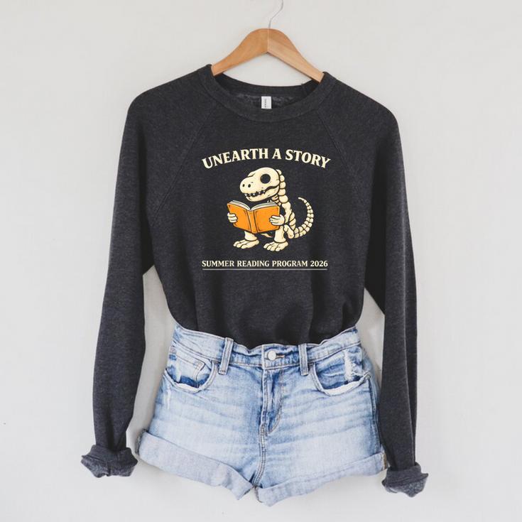 Dinosaur Books Readers Summer Reading 2026 Unearth a Story Raglan Sleeve Sweatshirt
