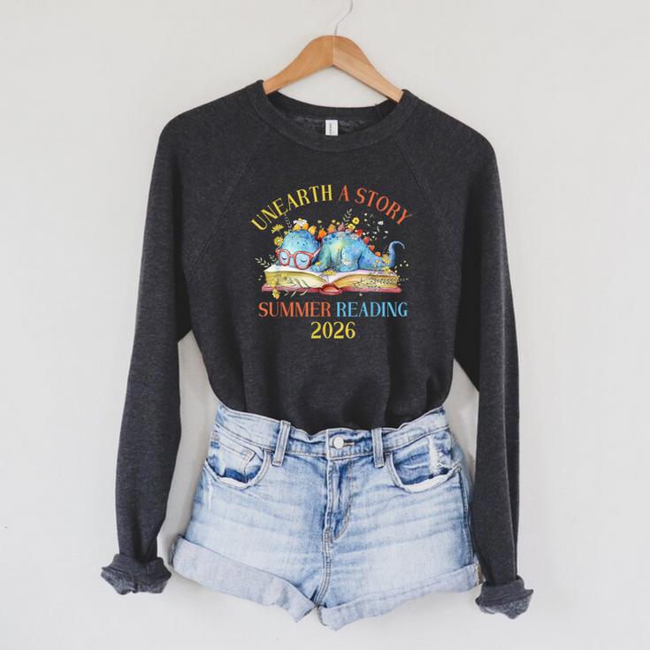 Unearth a Story Summer Reading 2026 Dinosaur Books Dino Raglan Sleeve Sweatshirt Unearth a Story Summer Reading 2026 Dinosaur Books Dino Raglan Sleeve Sweatshirt