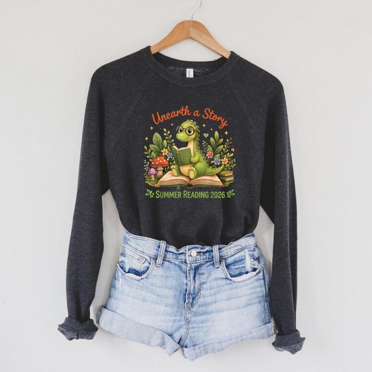 Unearth A Story Summer Reading 2026 Dinosaur Reading Books Raglan Sleeve Sweatshirt