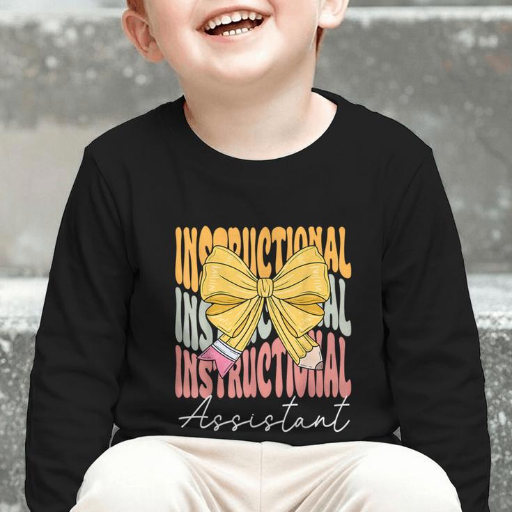Instructional Assistant Groovy Coquette Bow Back To School Graphic Toddler Long Sleeve Tee Instructional Assistant Groovy Coquette Bow Back To School Graphic Toddler Long Sleeve Tee