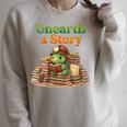 Women's Unearth a Story Summer 2026 Dinosaur Reading Books Dino Raglan Sleeve Sweatshirt Heather Forest